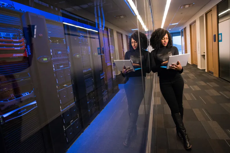 An engineer working on a tablet in the corridor beside a server room.