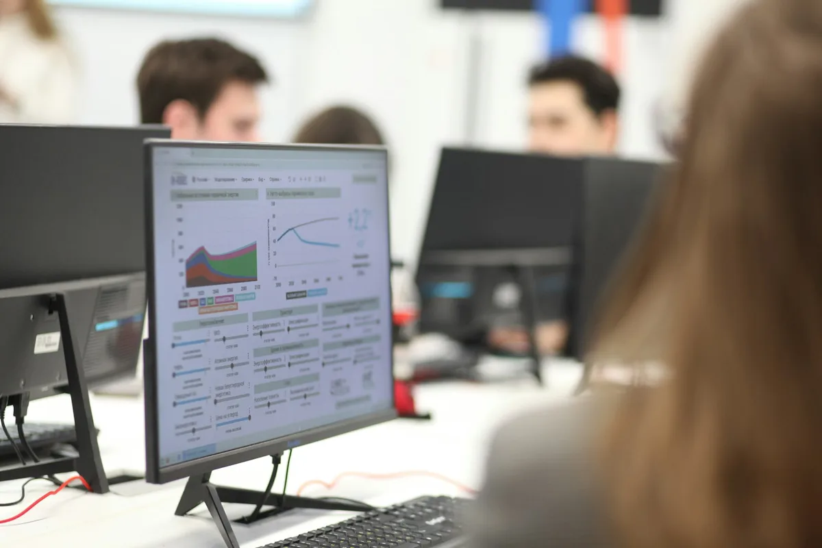 An analyst’s monitor showing reporting charts in a busy operations office.